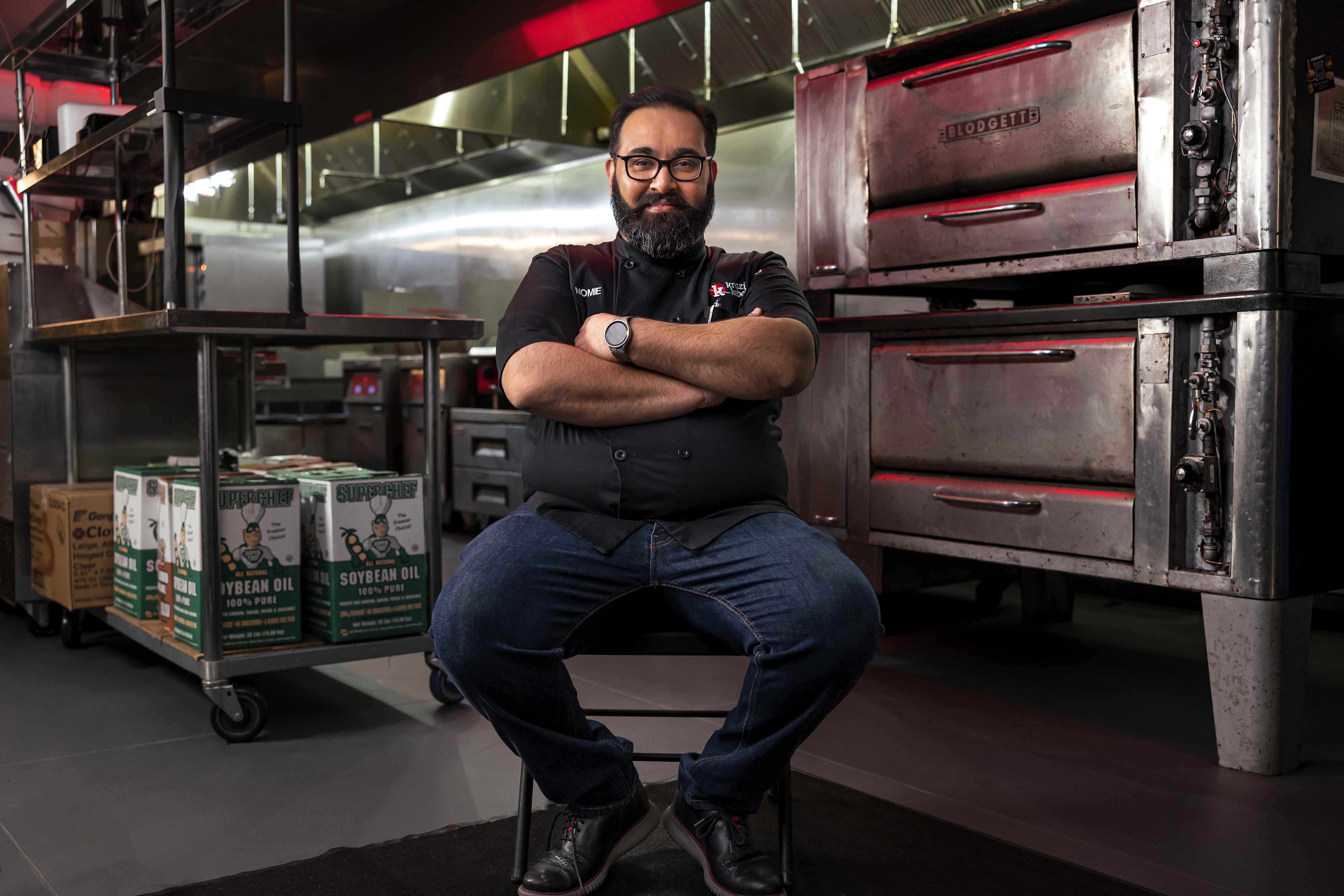 Chef Nomie seated in the VXK kitchen with arms crossed
