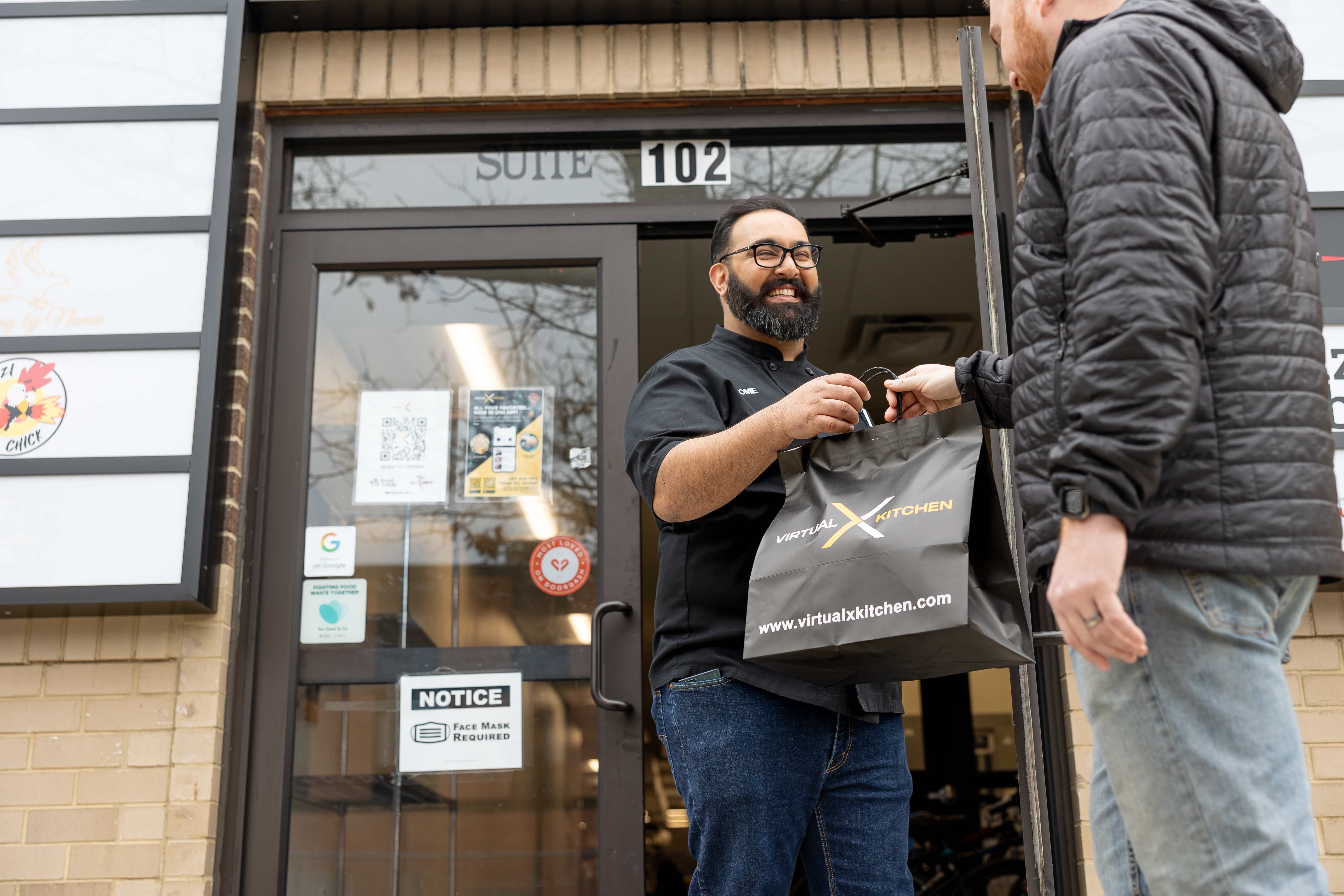 Chef Nomie handing a VXK delivery bag to a customer