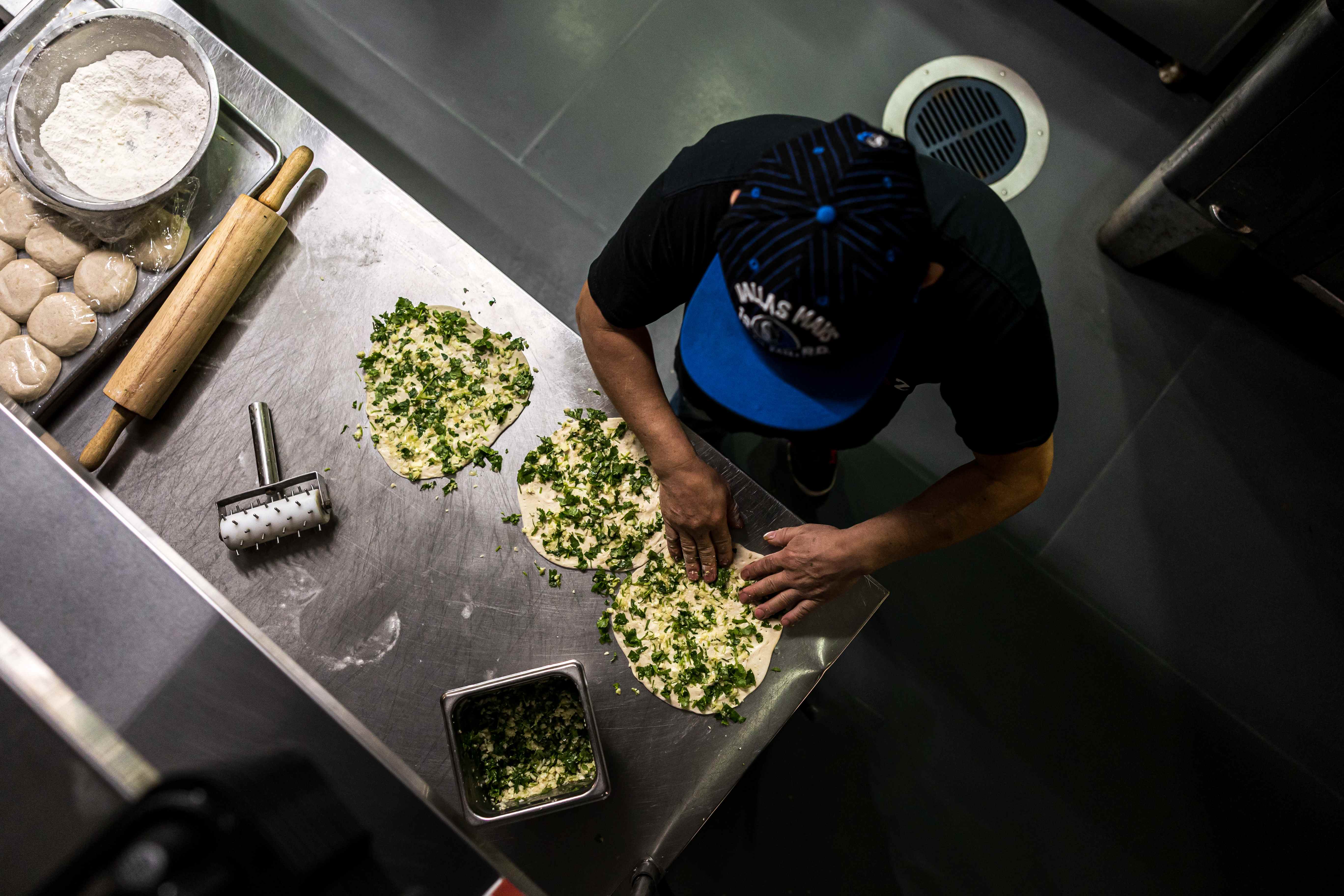 Chef preparing fresh naan bread with herbs and cilantro
