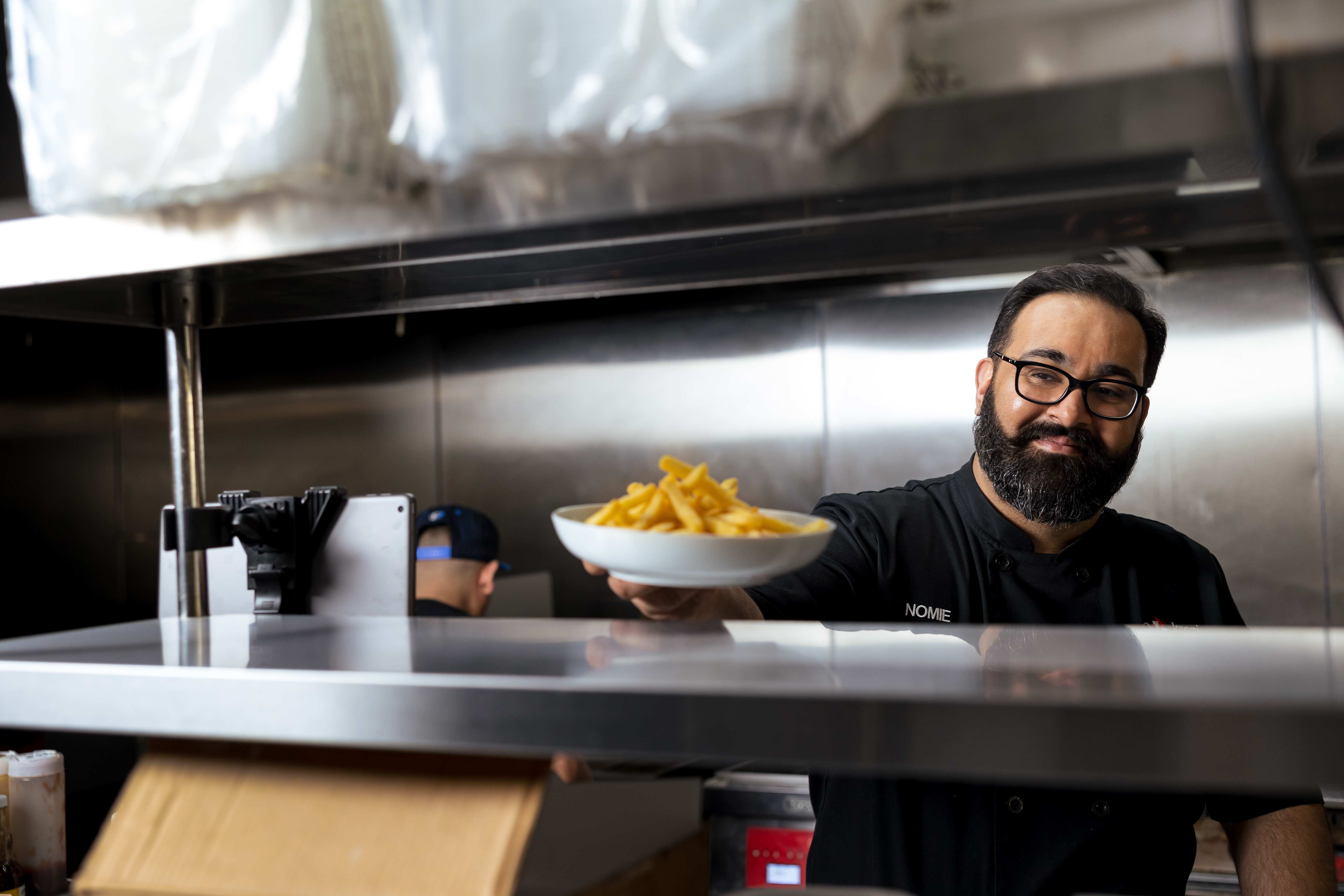 Chef Nomie serving fresh fries through the kitchen pass